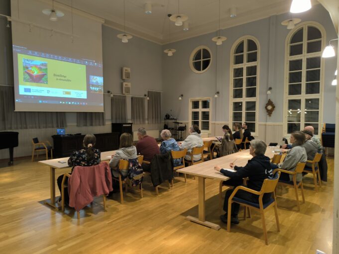 Ihmisiä salissa kuuntelemassa esitystä ympäristöaiheista.